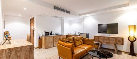 Una sala de estar moderna con un sofá de cuero, una mesa de centro, un televisor montado en la pared y un mueble de madera.