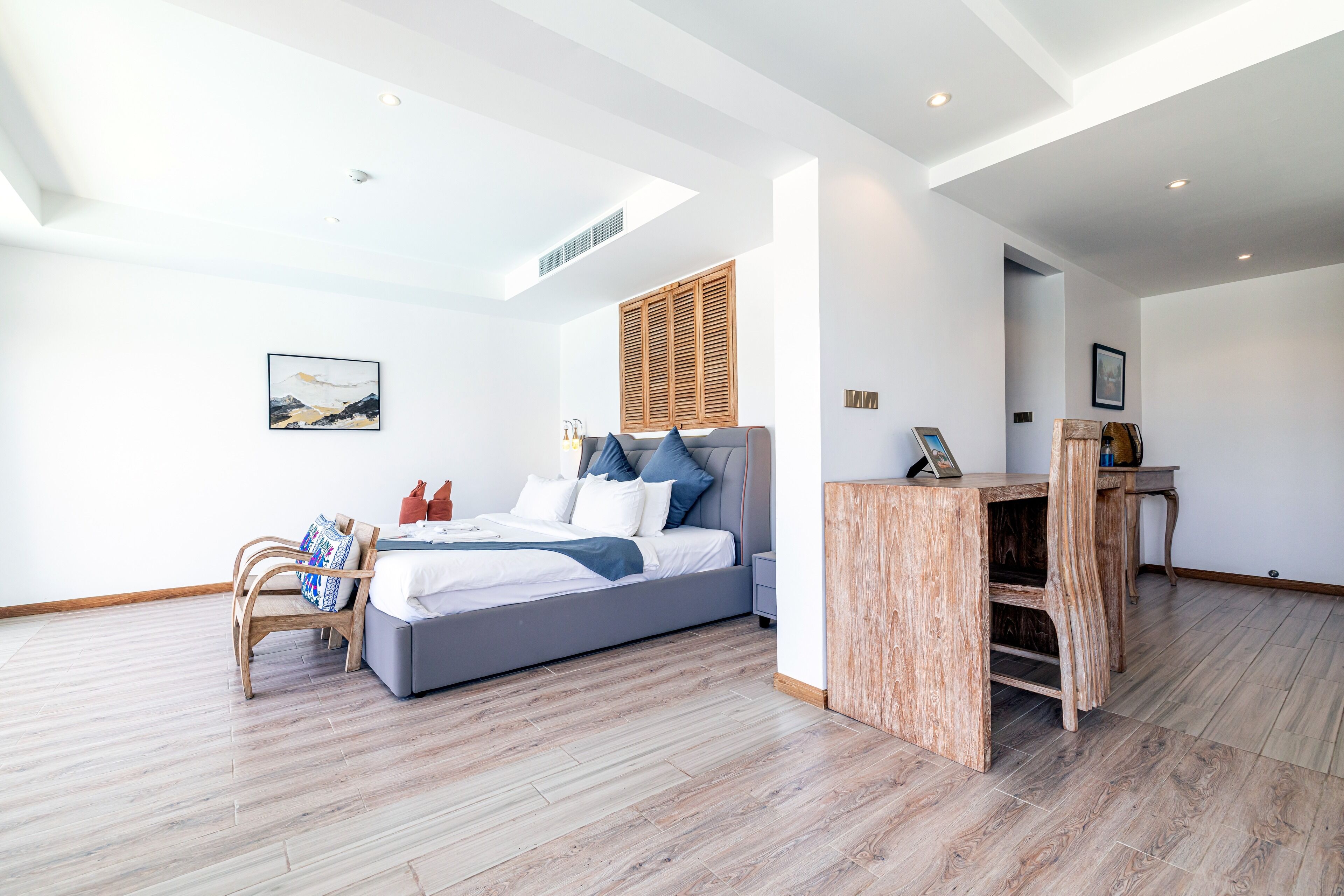 Une chambre moderne avec un grand lit, une tête de lit en bois et une petite table en bois.