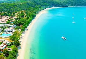 An aerial view of a coastal resort with a sandy beach, a swimming pool, and several boats anchored in the water. - Royal Yao Yai Island Beach Resort -sha Extra Plus+ (Ko Yao)