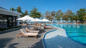 A poolside area with sun loungers and umbrellas, a clear blue pool, and palm trees in the background. - Royal Yao Yai Island Beach Resort -sha Extra Plus+ (Ko Yao)