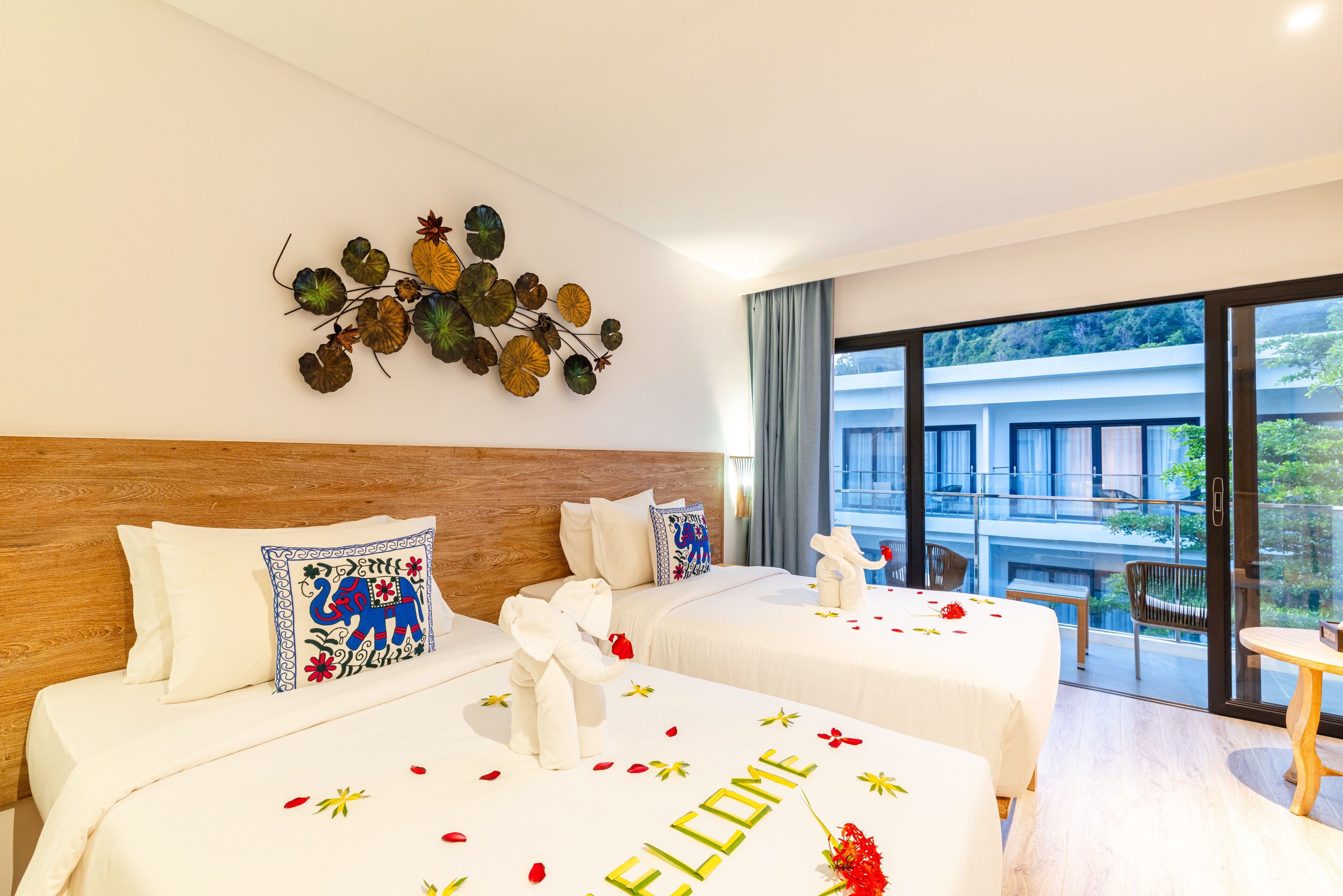Habitación de hotel con dos camas, un adorno en la pared y un balcón con vistas.