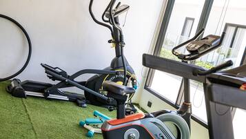 Uma academia com equipamentos de ginástica, incluindo esteira, bicicleta ergométrica e pesos.