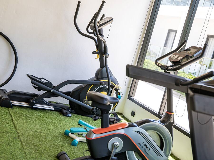 Uma academia com equipamentos de ginástica, incluindo esteira, bicicleta ergométrica e pesos.