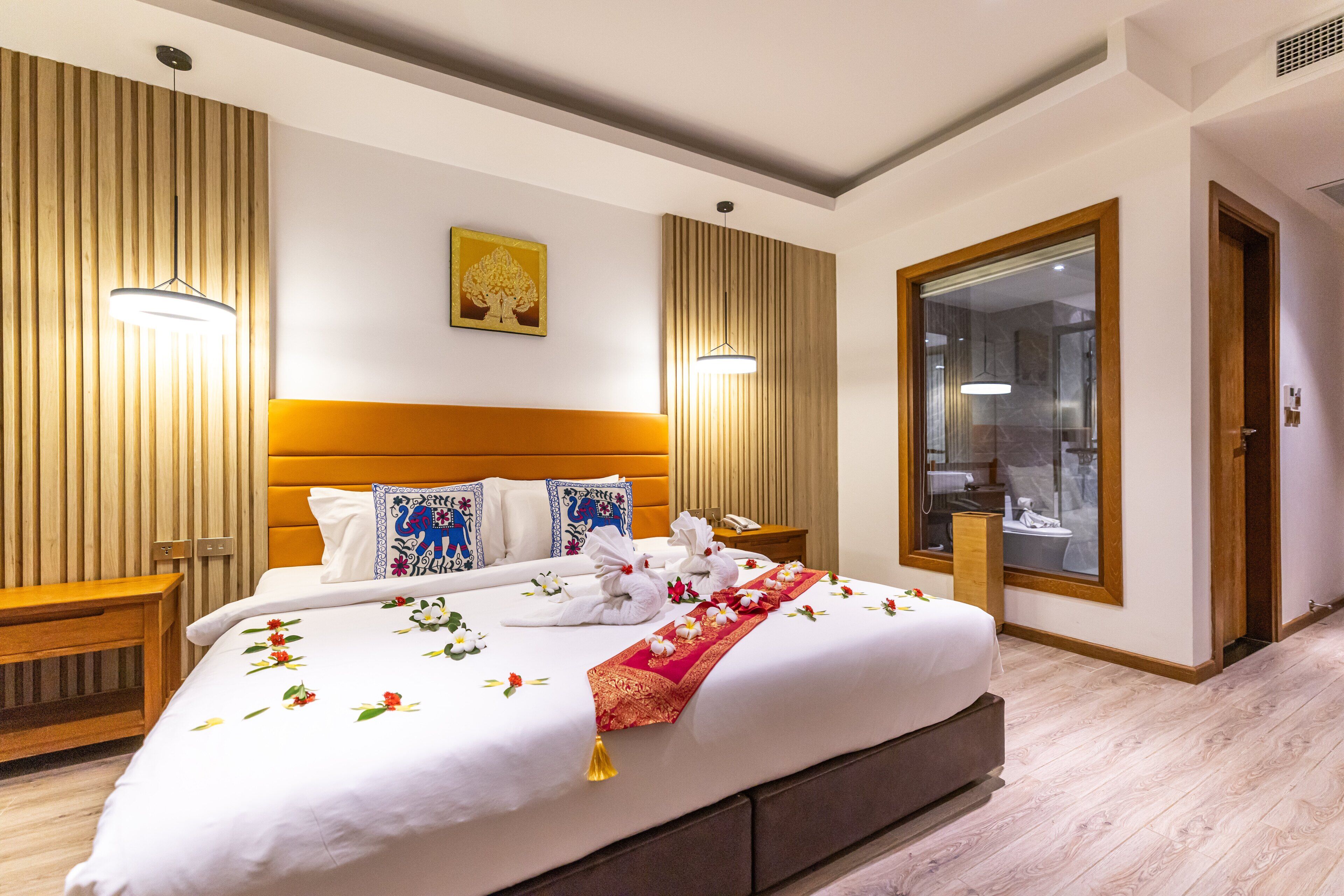Una habitación de hotel con una cama grande, cabecero de madera, mesitas de noche y un espejo.