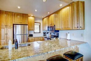 A kitchen with wooden cabinets, stainless steel appliances, granite countertops, and a built-in oven.