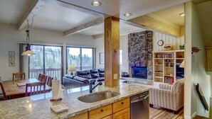 A spacious kitchen with granite countertops, wooden cabinets, and a stone fireplace. - Best Location - True Hike In/Out TH w/Private HotTub and Slope Views-Gas Fireplace-W/D in Unit (Steamboat Springs)