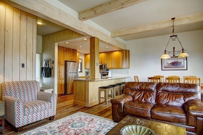 A living room with a brown leather sofa, patterned armchair, and a coffee table.