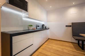 Une cuisine moderne équipée d’un four à micro-ondes, d’une machine à café et agrémentée d’une petite plante posée sur le plan de travail.