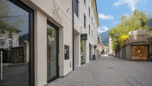 Una calle adoquinada con un edificio que presenta grandes ventanales y un letrero que dice 'RICE LIVING'.