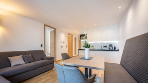 Una sala de estar moderna con un sofá, una mesa de comedor y una cocina al fondo.