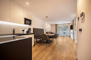 Una cucina moderna con zona pranzo, pavimento in legno e un'ampia finestra.