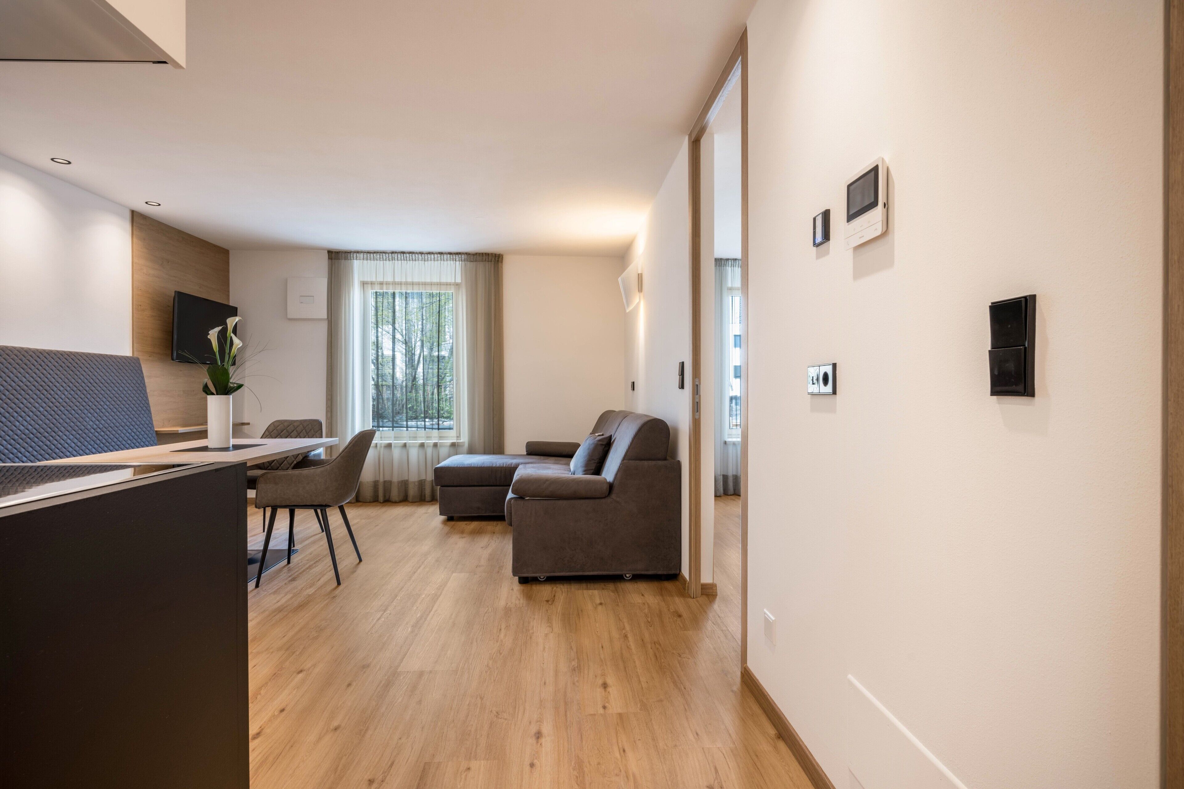 Un salon moderne comprenant un canapé, un coin repas et un téléviseur fixé au mur.