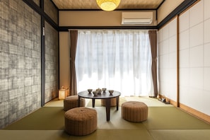 Experience traditional Japanese elegance in this serene room, featuring tatami flooring, shoji screens, and a round table with a tea set.