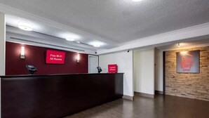 A reception area with a dark reception desk, two signs indicating free Wi-Fi in all rooms, and a Red Roof sign on the wall. - Red Roof Inn Houston North - Fm1960 and I-45 (Houston)