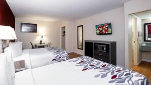 A hotel room with two beds, a desk with a lamp, a TV, and a framed picture on the wall. - Red Roof Inn Houston North - Fm1960 and I-45 (Houston)