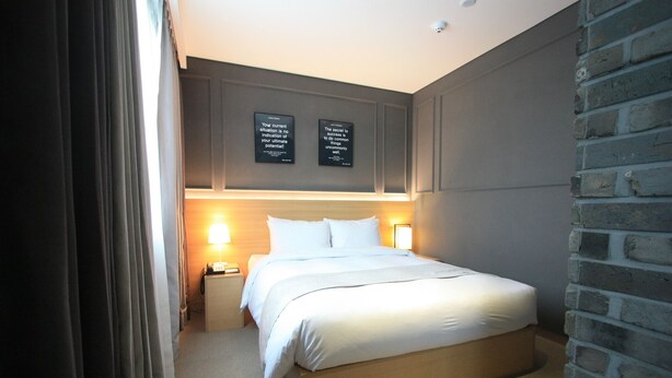 A hotel room with a bed, bedside lamps, and two motivational posters on the wall. - Suwon Vella Suite Hotel (Suwon)