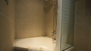 A bathroom with a bathtub, shower, and glass-enclosed shower area. - Suwon Vella Suite Hotel (Suwon)