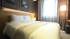 A hotel room with a large bed, a nightstand with a lamp, and motivational posters on the wall. - Suwon Vella Suite Hotel (Suwon)