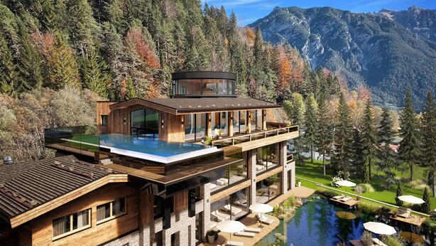 A modern house with a glass infinity pool, wooden deck, and a mountain backdrop. - Kuschel-chalet - Chalets Grossmitt (Pertisau)