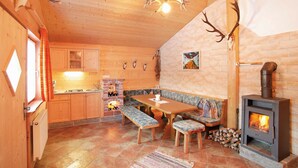 A cozy cabin interior with a wooden dining table, benches, a fireplace, and antler decorations. - Kuschel-chalet - Chalets Grossmitt (Pertisau)