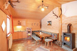 Een gezellig houten vakantiehuisje met een eettafel, bankjes, een open haard en decoraties van gewei.