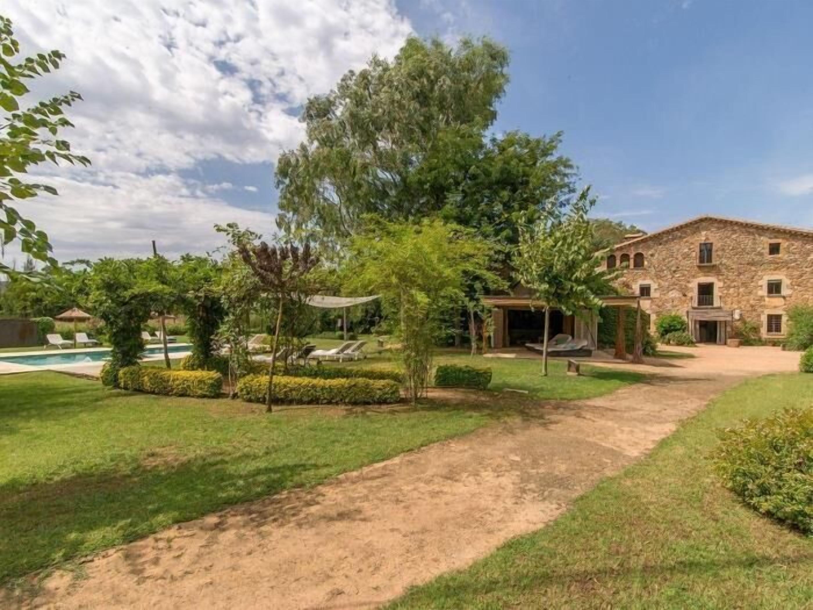 Un bâtiment en pierre doté d’un jardin, d’une piscine et surplombant un ciel dégagé.