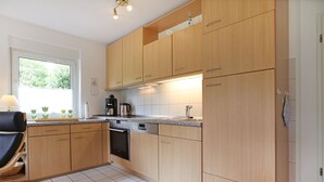 Eine moderne Küche mit Holzschränken, einem Einbauofen und einer Kaffeemaschine.