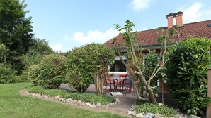 Ein Garten mit Terrasse, einem Backsteinhaus und einem Weg.
