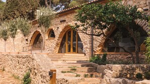 A stone building with arched windows and a large terracotta pot in front. -  Wecamp Cala Montgó (L'Escala)