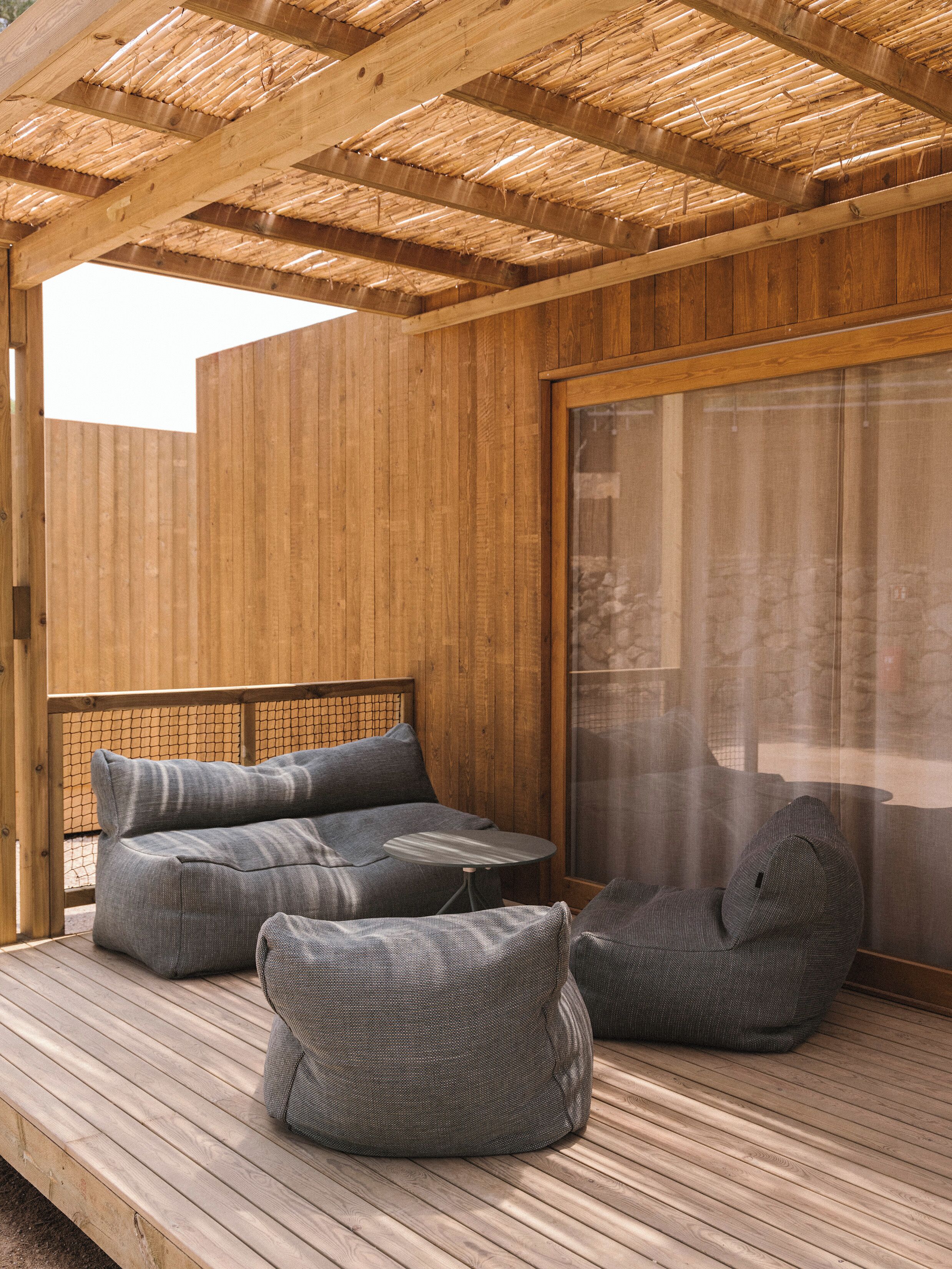 Une terrasse en bois avec des sièges, une porte-fenêtre coulissante et un plafond en bambou.