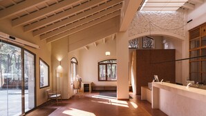 A spacious lobby with a high ceiling, large windows, and a reception desk. -  Wecamp Cala Montgó (L'Escala)