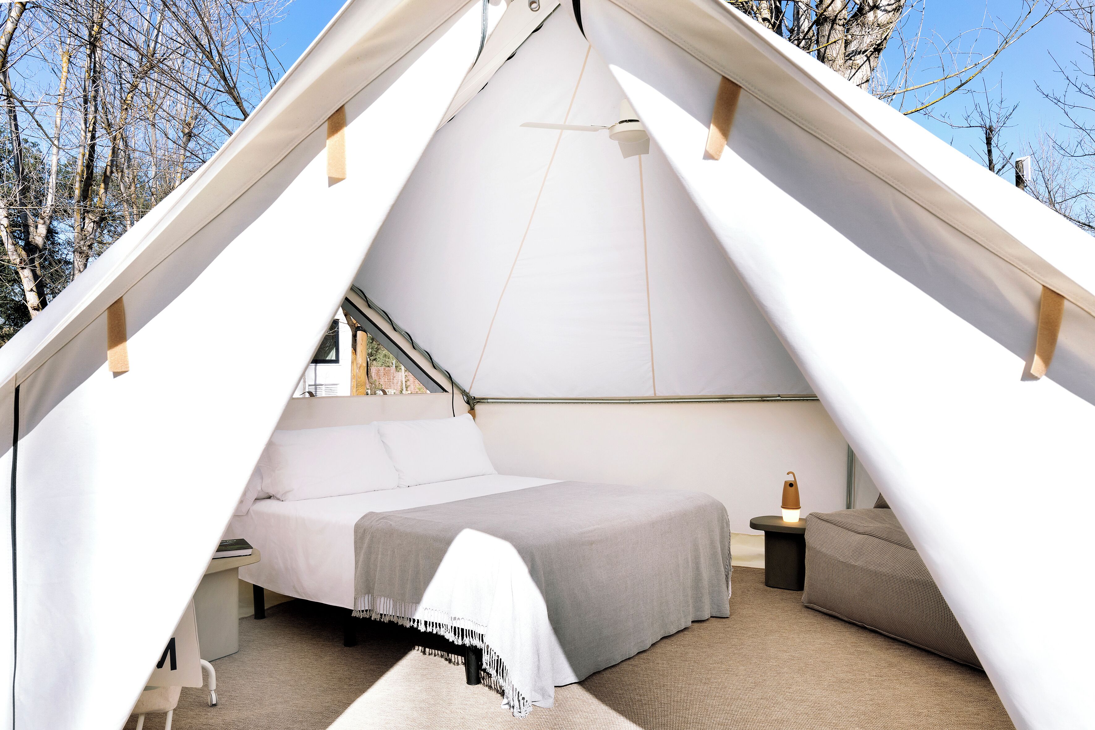 A tent with a bed, a nightstand, and a lamp.