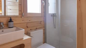 A wooden cabin bathroom with a sink, toilet, and glass shower enclosure.