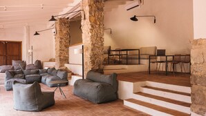 A spacious living area with a stone column, grey sofas, a dining table with chairs, and a laptop on the table. -  Wecamp Cala Montgó (L'Escala)