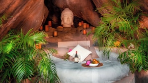 Un endroit paisible, agrémenté d’une statue de Bouddha, de bougies et d’un petit autel sur lequel on trouve une bouteille et des fruits.