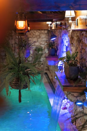 A room with a stone wall, a hanging fern, and a small waterfall feature.