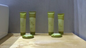 Une étagère de salle de bain avec trois flacons de produits de toilette verts.
