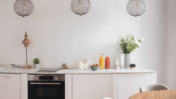 A modern kitchen with a built-in oven, a dining table, and three hanging pendant lights.
