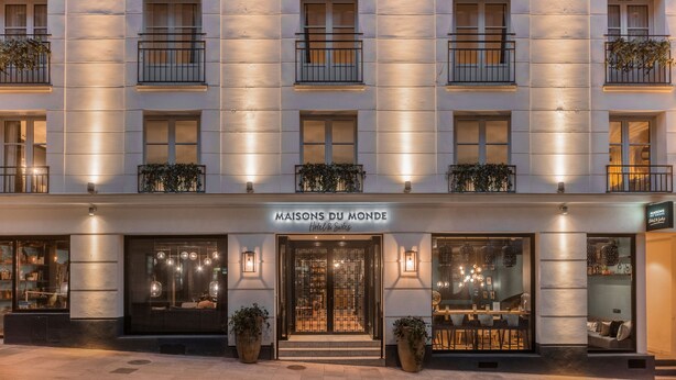Fachada de hotel con balcones, ventanas amplias y un letrero que dice 'MAISONS DU MONDE Hotel & Suites'.