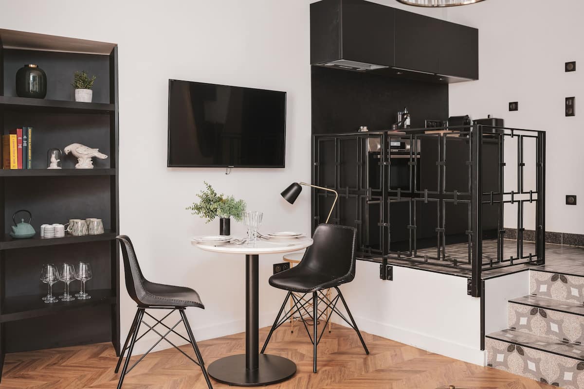 Una cocina moderna con una estufa negra, un televisor de pantalla plana y un comedor con dos sillas y una mesa.