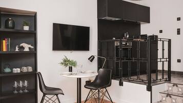 Una cocina moderna con una estufa negra, un televisor de pantalla plana y un comedor con dos sillas y una mesa.