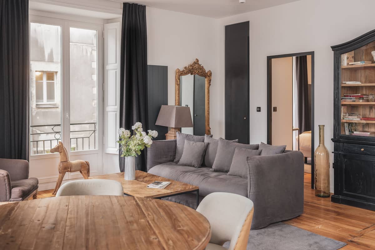 Una sala de estar moderna con un sofá gris, una mesa de centro de madera y una lámpara.