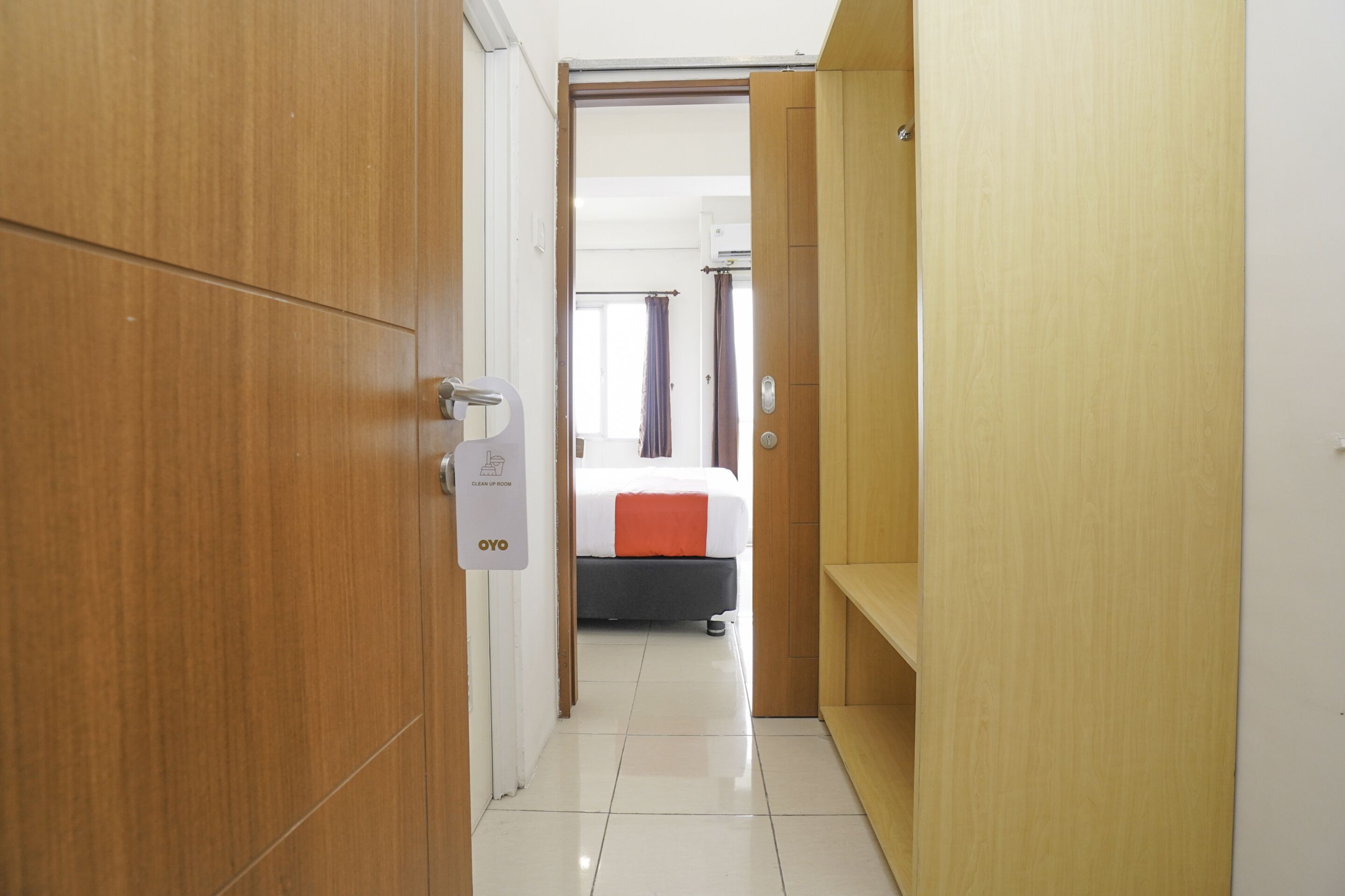 A hotel room with a bed, a wardrobe, and a clean tiled floor.