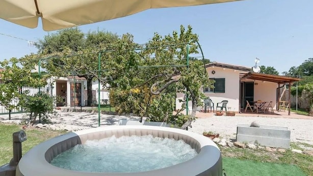 A hot tub in a backyard with a house, outdoor furniture, and a pergola. - Villa LA CASETTA for 4-6 persons - with jacuzi (San Felice Circeo)