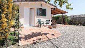 A small building with a white exterior, a door, and a window with green shutters. There are two green plastic chairs outside. - Villa LA CASETTA for 4-6 persons - with jacuzi (San Felice Circeo)