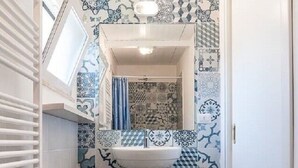 A bathroom with a white sink, a mirror above it, and patterned tiles on the walls and floor. - Villa LA CASETTA for 4-6 persons - with jacuzi (San Felice Circeo)