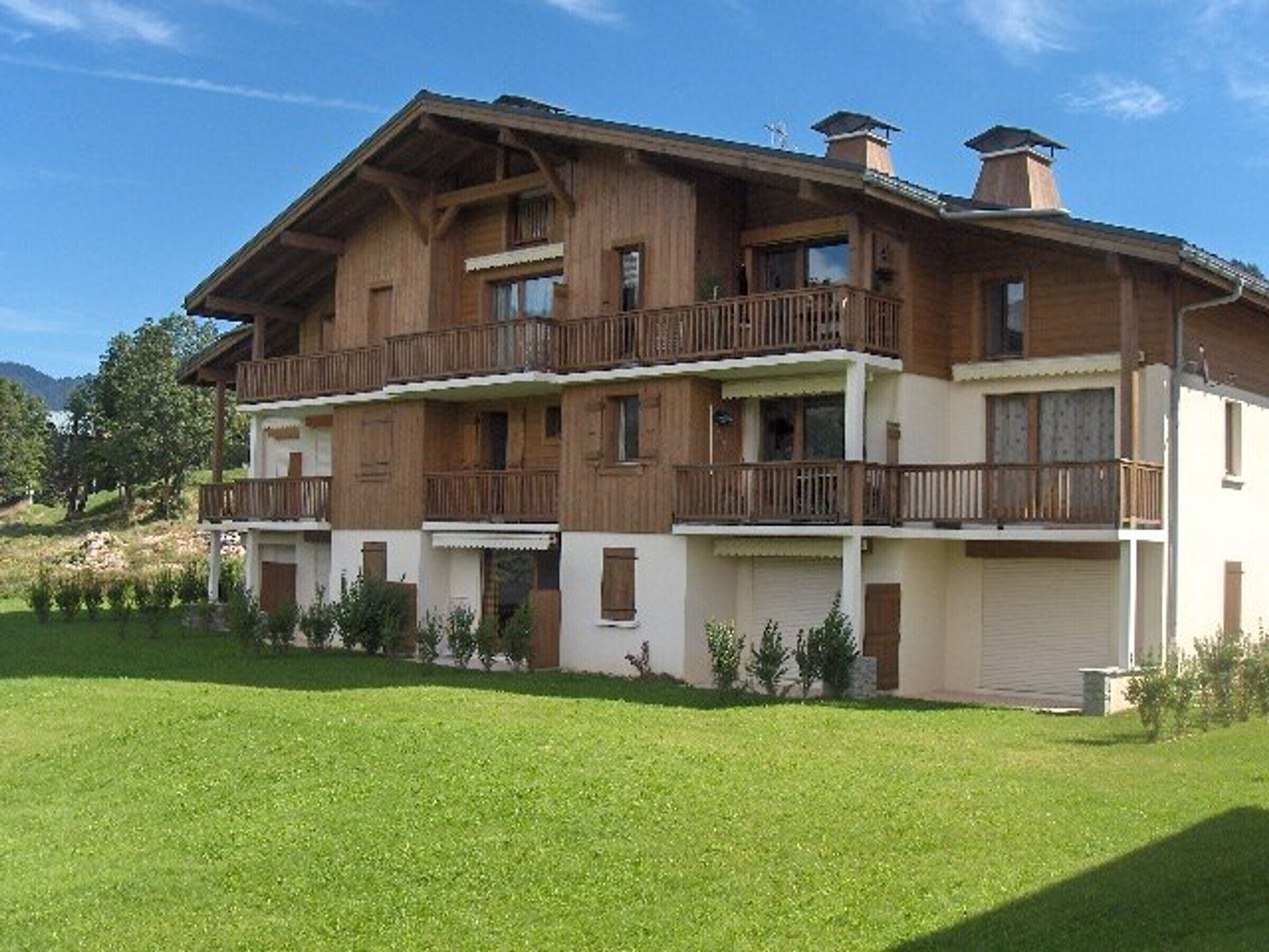 A multi-story wooden building with balconies, surrounded by a well-maintained lawn.