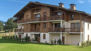 Un edificio de madera de varios pisos con balcones, rodeado por un césped bien cuidado.
