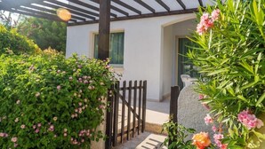 A white building with a wooden pergola, a stone wall, and a gate. - Paphos Gardens Apartments (Paphos)