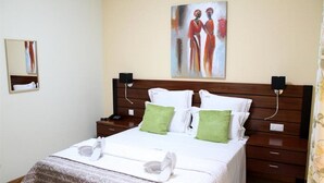 Un cuarto de hotel con una cama grande, un cabecero de madera, dos mesitas de noche y un cuadro en la pared.
